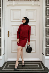 a lady wears a red tweed jacket with matching mini skirt